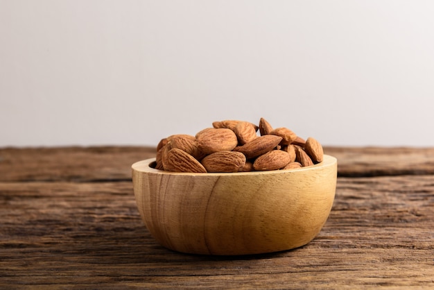 Group of Peeled almonds in wooden bowl on rustic wooden table. Almonds background.