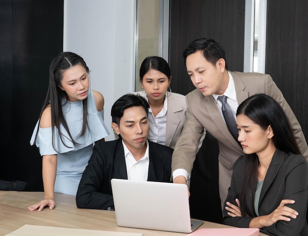 Foto un gruppo di persone è riunito attorno a un laptop e uno di loro lo sta guardando.