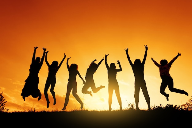 Photo a group of people are jumping against the sunset