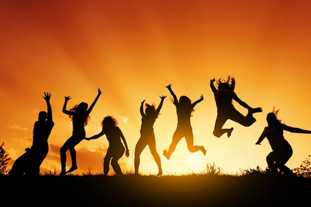 A group of people are jumping against the sunset