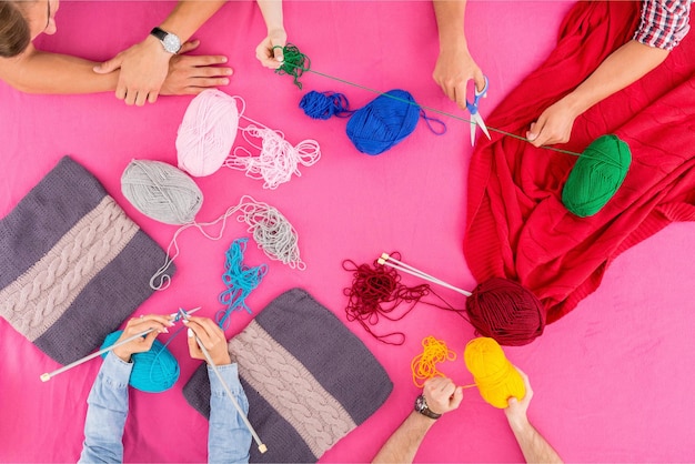 A group of people are sitting around a table with knitting yarns.