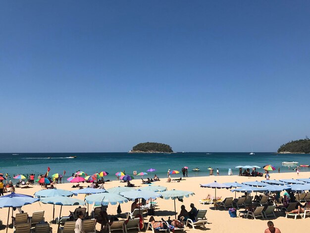 Group of people on beach against blue sky