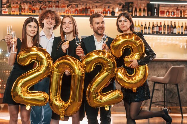 Photo group of people in beautiful elegant clothes are celebrating new year indoors together