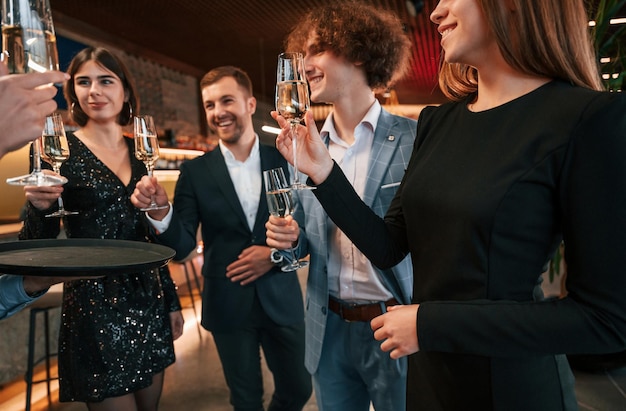 Photo group of people in beautiful elegant clothes are celebrating new year indoors together