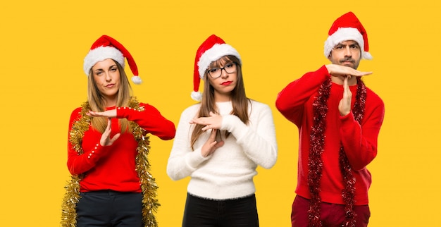 A group of people Blonde woman dressed up for christmas holidays making stop gesture 