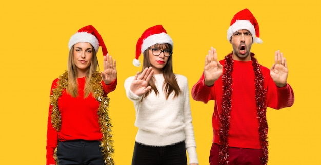 A group of people Blonde woman dressed up for christmas holidays making stop gesture