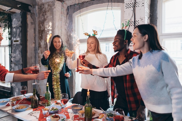 Group of people celebrating christmas or new year eve. friends\
toasting drinks and enjoying dinner together.