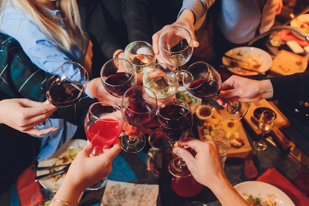 group of people clinking glasses with wine or champagne