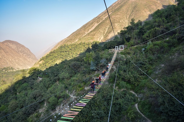 Group of people crossing a TIBETAN BRIDGE tourist attraction in San Mateo de Otao Peru