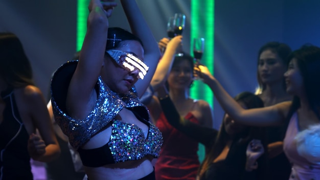 Группа людей танцует в ночном диско-клубе под музыку ди-джея на сцене