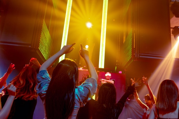Group of people dance in disco night club to the beat of music\
from dj on stage