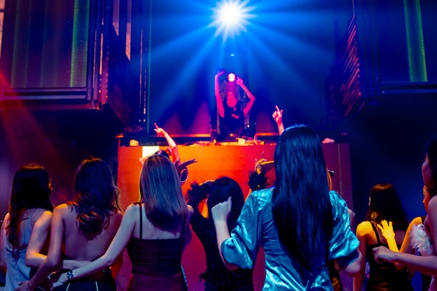 Group of people dance in disco night club to the beat of music\
from dj on stage