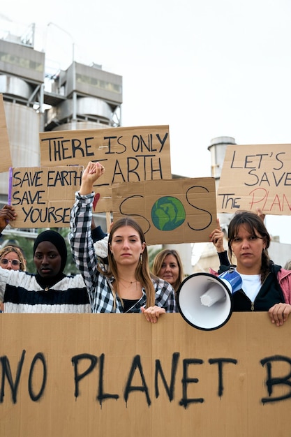 Group of people of different ages and nationalities with arms raised in protest against pollution