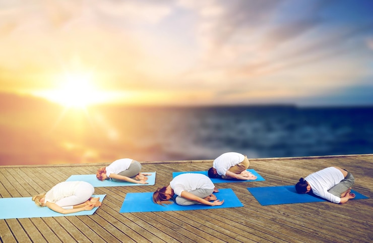 Photo group of people doing yoga child pose outdoors