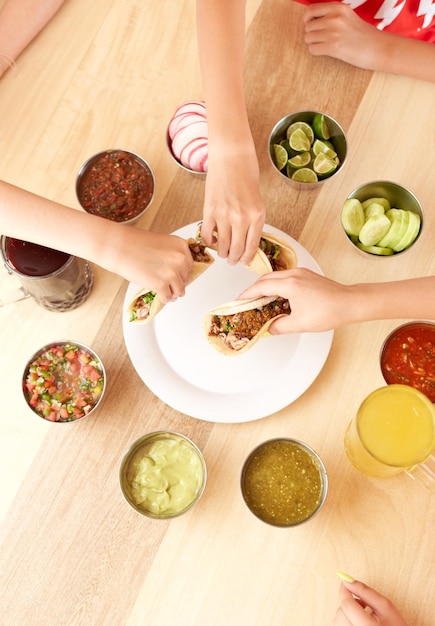 Gruppo di persone che mangiano deliziosi tacos al pastor con salsa e una varietà di ingredienti