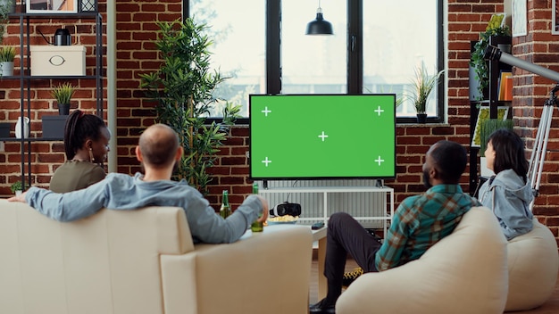 Photo group of people enjoying movie on television with greenscreen template, having fun at gathering. watching cinema tv film with isolated chroma key background and blank mockup at home.