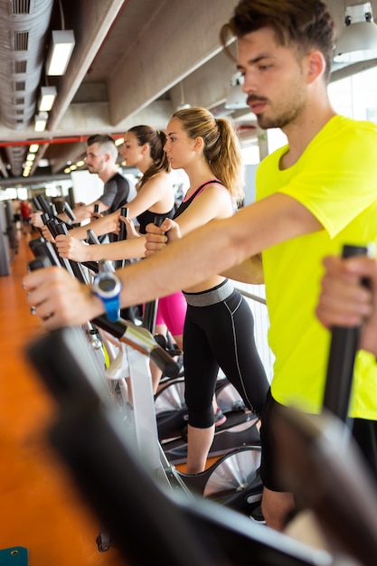 Group of people exercising their legs doing cardio training in gym.