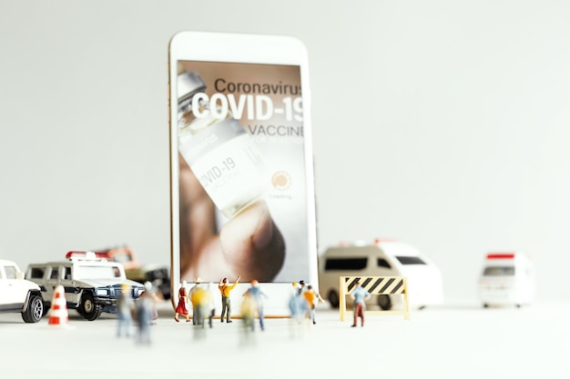 Group of people (figurine) watching on smartphone during COVID vaccine aplication.