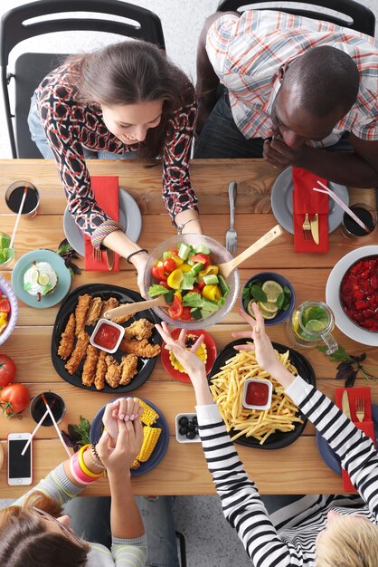 Group of people having dinner together while sitting at wooden table