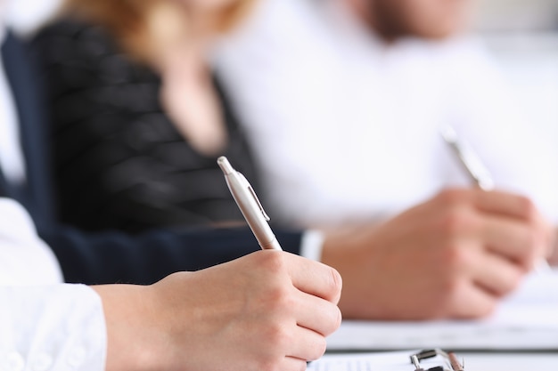 Group of people hold silver pen ready to make