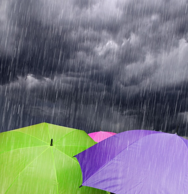 a group of people holding umbrellas under a cloudy sky in the rain with a dark sky in the backgroun