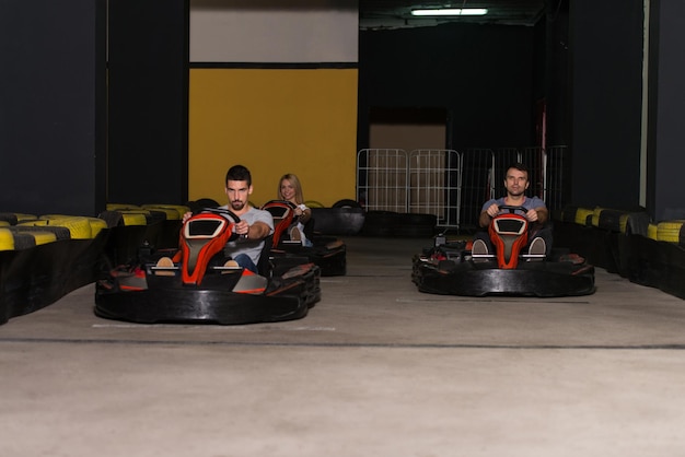 Photo group of people is driving gokart car with speed in a playground racing track  go kart is a popular leisure motor sports