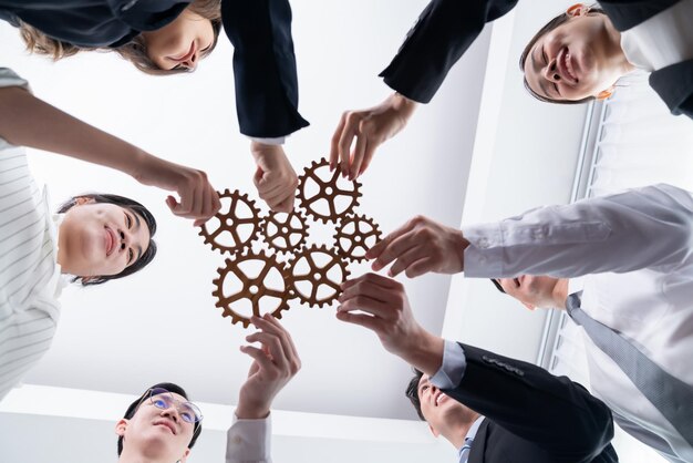 Group of people making chain of gears into collective form for harmony symbol