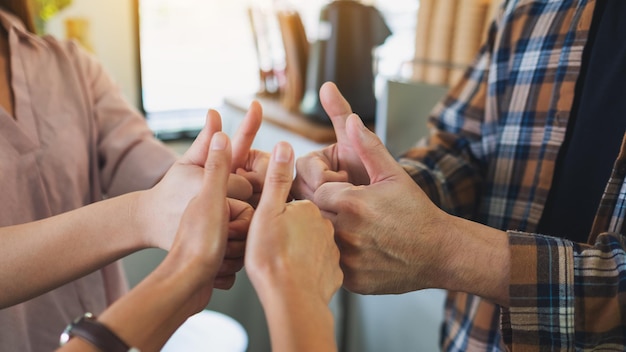 Photo a group of people making thumb up hands sign in circle