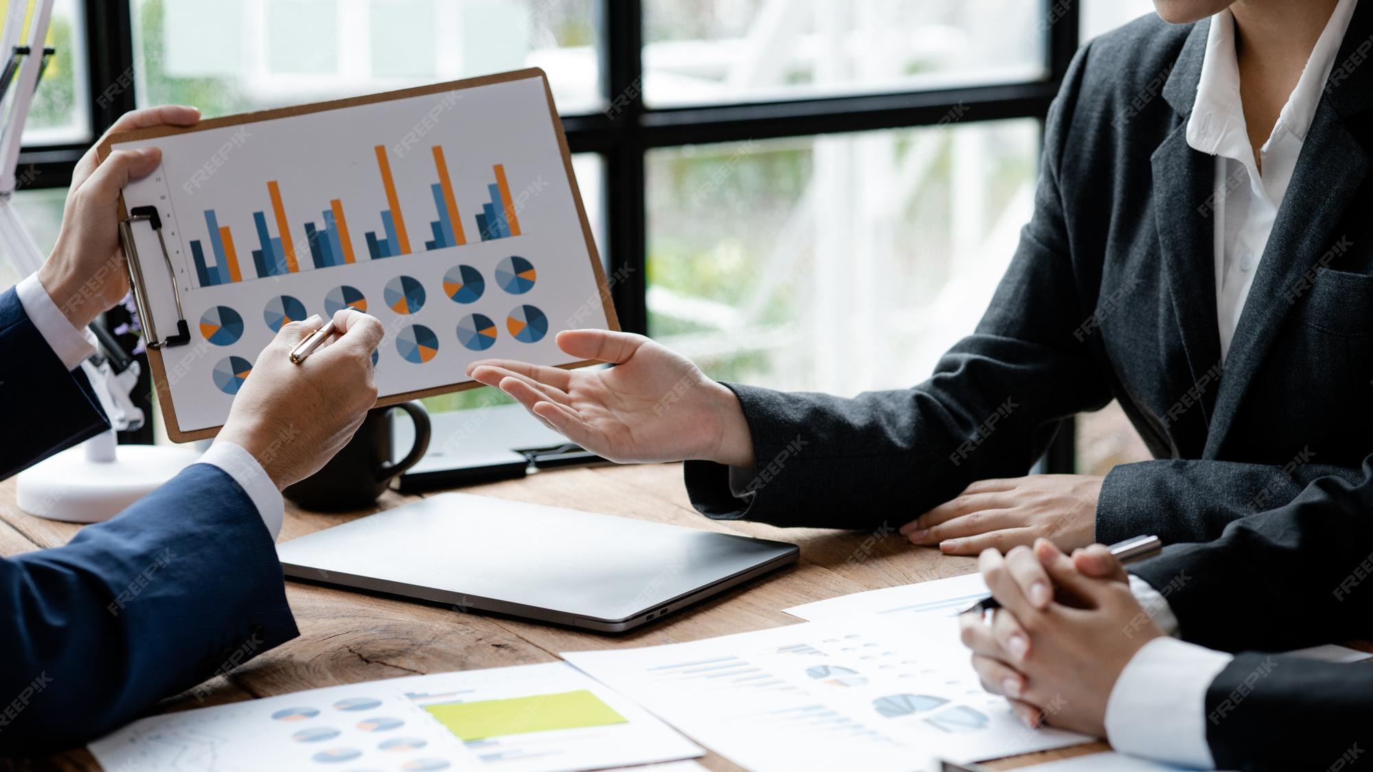 Premium Photo | A group of people pointing to papers on a table in a conference room a financial analyst attending a company audit meeting with the finance and accounting department meeting