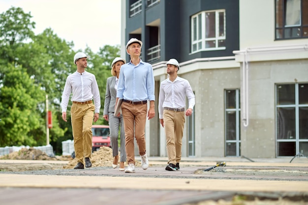 Group of people in protective helmets walking along construction site