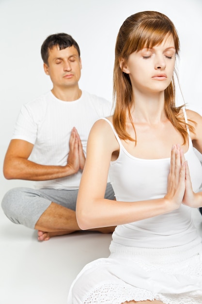 Group of people relaxing and doing yoga in white studio