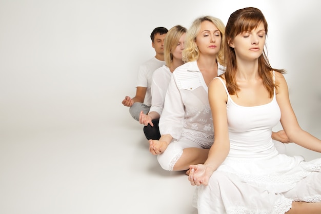 Group of people relaxing and doing yoga in white