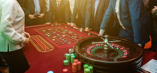 Gruppo di persone dietro il tavolo da gioco della roulette nel casinò di lusso