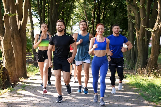 Group of people running in park on sunny day
