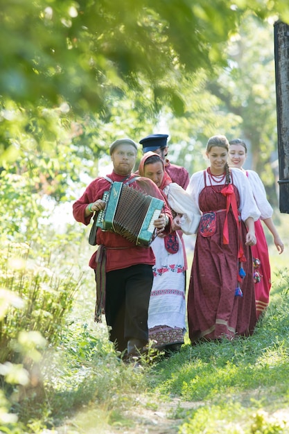 Foto un gruppo di persone in costumi popolari russi che passeggiano per un bellissimo villaggio