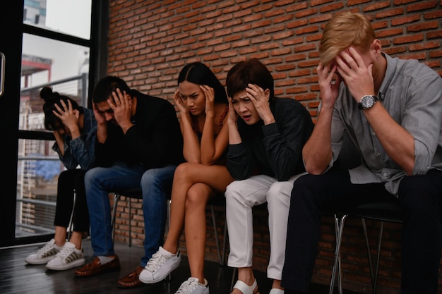 Photo group of people sitting against wall