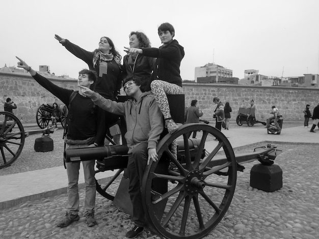 Group of people sitting on a cannon exhibit in a museum.