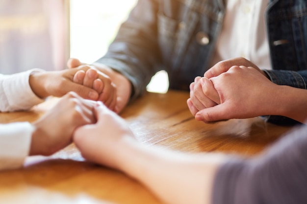 Gruppo di persone sedute in cerchio che si tengono per mano e pregano insieme o in una sessione di terapia