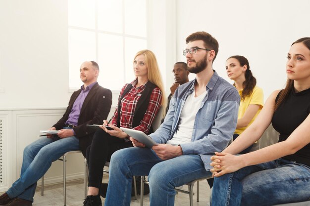 Group of people sitting at seminar, copy space. Serious and concentrated audience listening to speaker. Education, conference, workshop concept