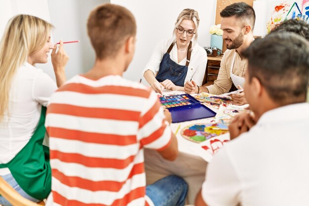 Foto gruppo di persone che sorridono felice disegno seduto sul tavolo in studio d'arte