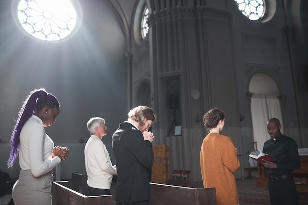 Foto gruppo di persone in piedi in chiesa durante una messa con il sacerdote