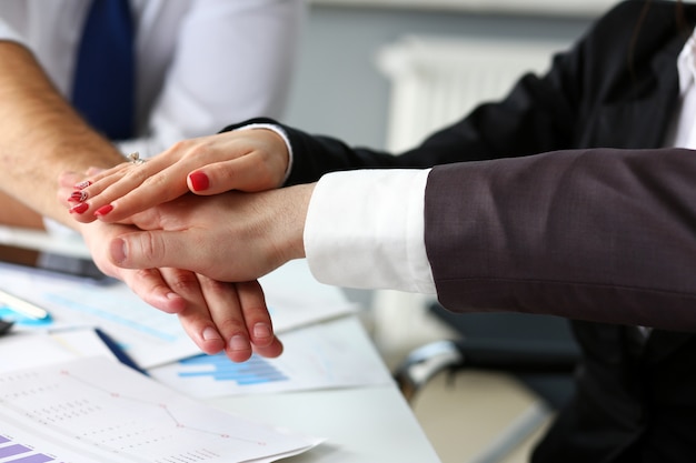 Group of people in suits crossed hands in pile