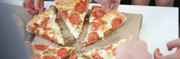 Group of people taking slices of pizza closeup