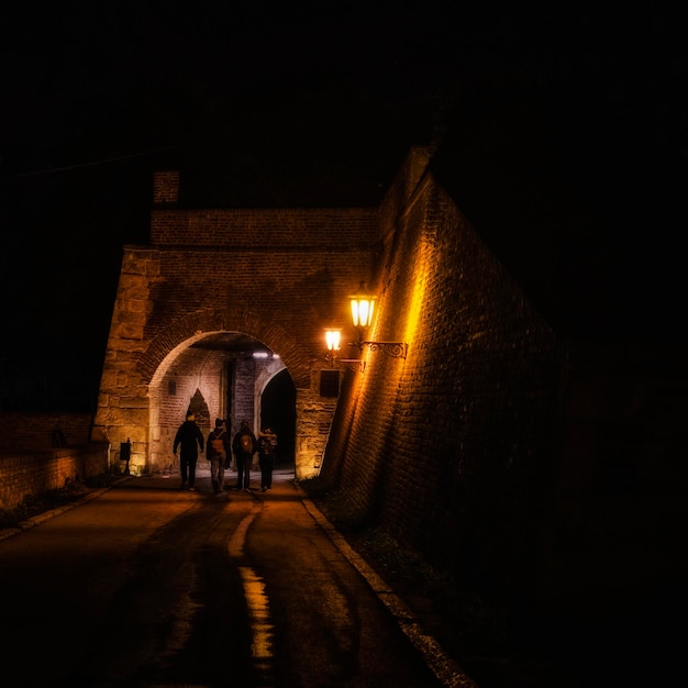 A group of people walking under a bridge with a light on it