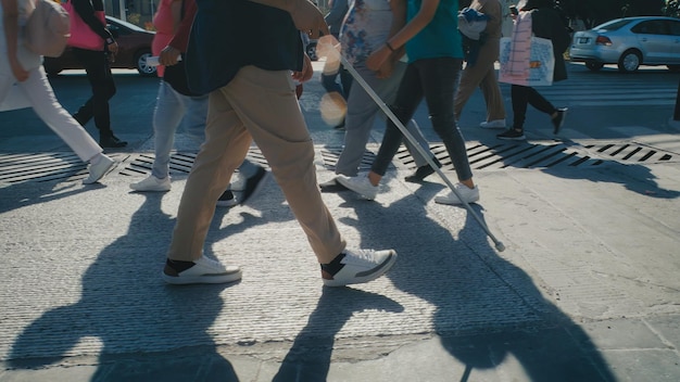 A group of people walking down a street, one of them is wearing white shoes.