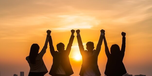 A group of people with arms raised in the air, with the sun behind them.