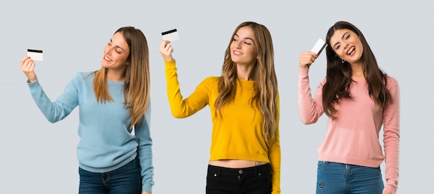 Group of people with colorful clothes holding a credit card and thinking on colorful background