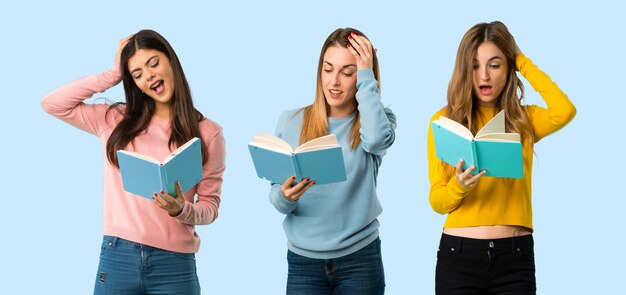 Group of people with colorful clothes surprised while enjoying reading a book on colorful background