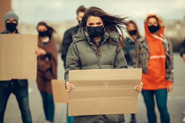 Un gruppo di persone con maschera e poster per protestare la protesta della popolazione contro il coronavirus e contro l'introduzione della quarantena