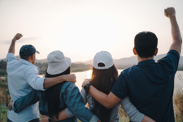 산 배경에서 일출을 바라보는 팔을 들고 있는 사람들